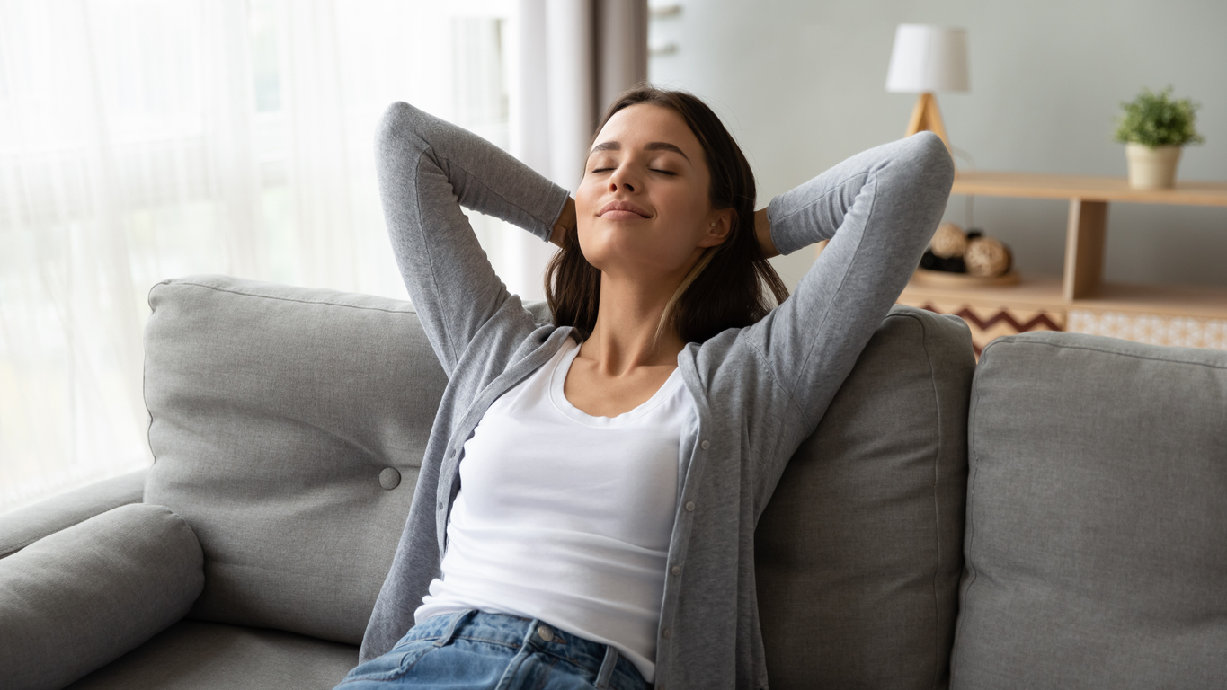 Woman relaxing on sofa with hands behind head